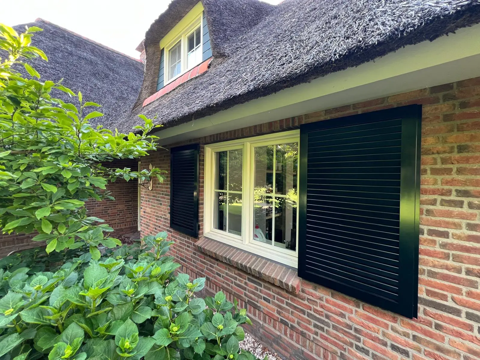 Zwarte aluminium louvre luiken aan rietgedekte boerderij — Shutters Inc.
